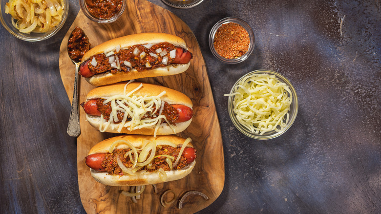Three chili cheese dogs on a board
