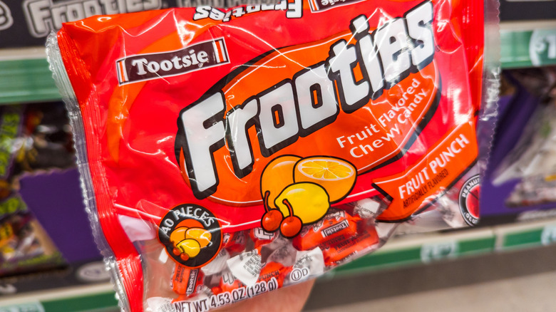 Someone holding up a package of Fruit Punch flavored Frooties candies at the grocery store