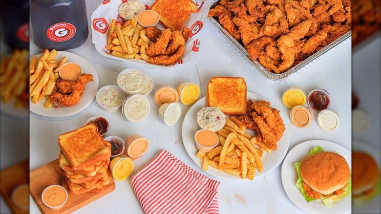 A tray of Guthrie's chicken fingers beside Texas toast, dipping sauces, fries, and iced tea