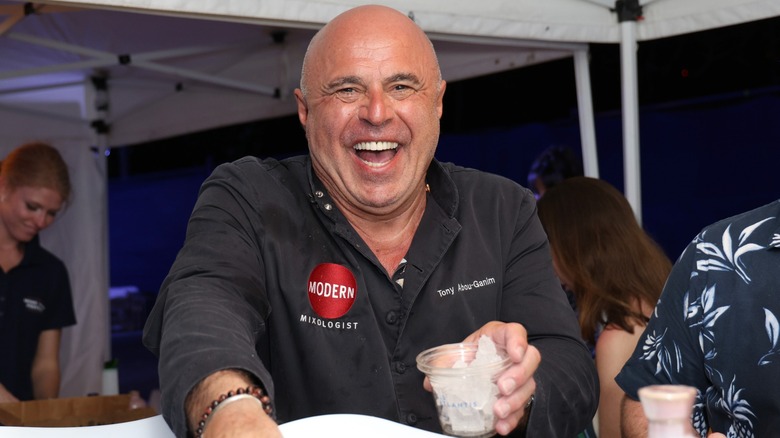 Tony Abou-Ganim holding a drink and laughing