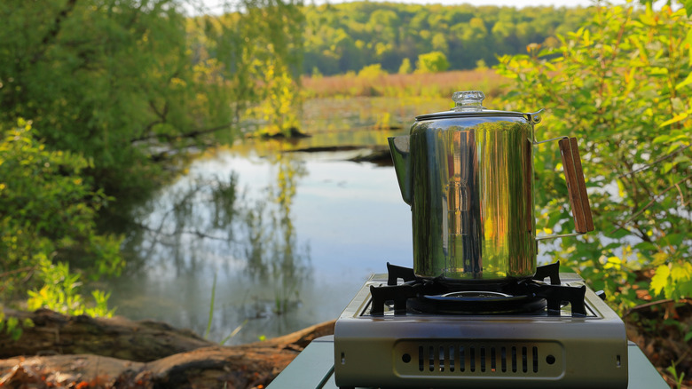 Percolator coffee maker on a stovetop outside for camping