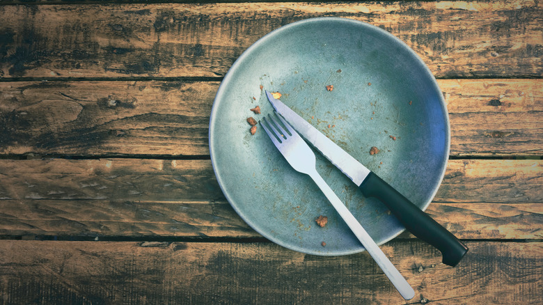 A dirty plate with cutlery on wooden table