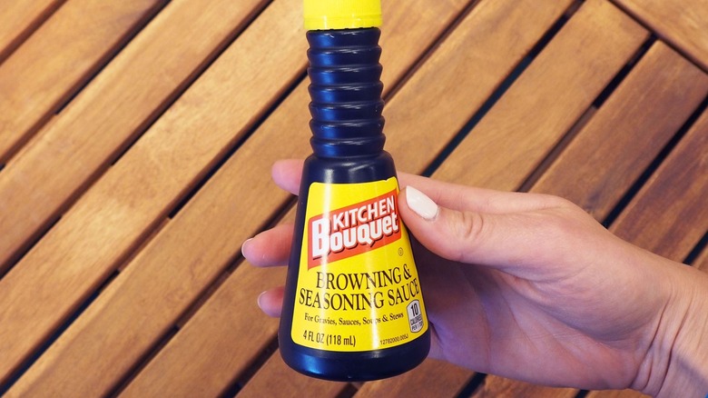 Hand holding a bottle of Kitchen Bouquet browning sauce