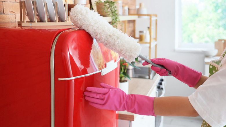 woman dusting retro red refrigerator