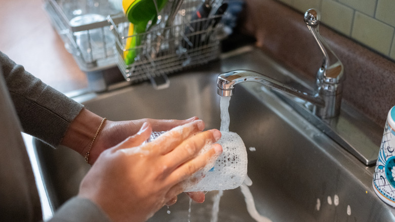 A man washing a glass in the sink