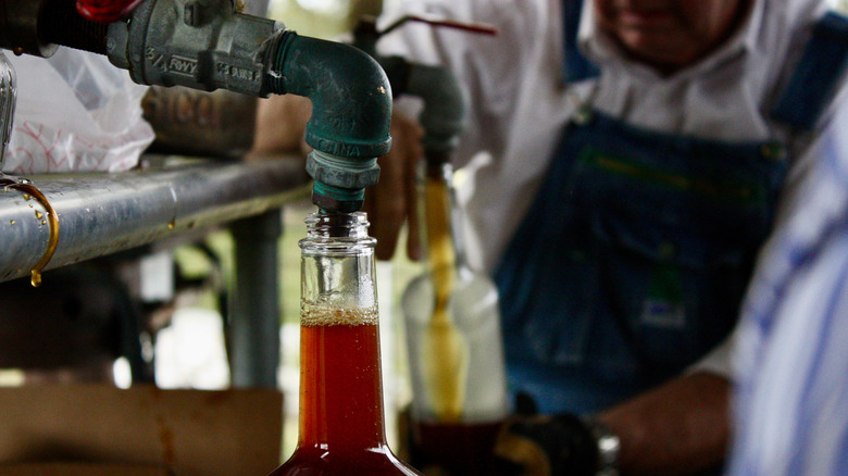 Cane syrup being bottled by a person in overalls