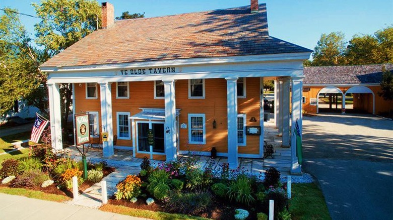 Outside view of Ye Olde Tavern with its gardens and old American flags