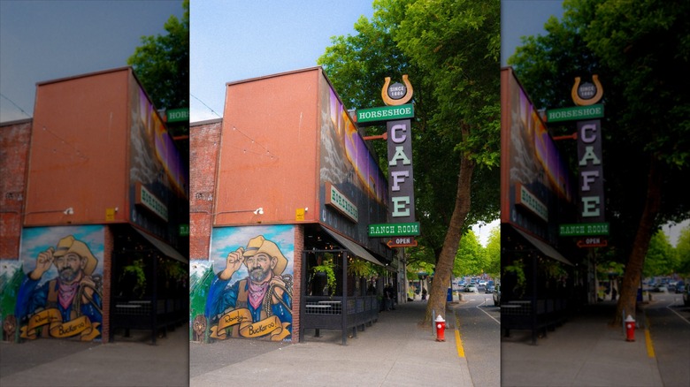Sidewalk view of Horseshoe Cafe with mural, outdoor patio dining, and colorful sign
