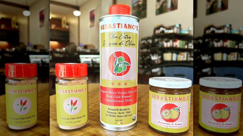 A bottle of Sebastiano's olive oil besides other products on a deli table.