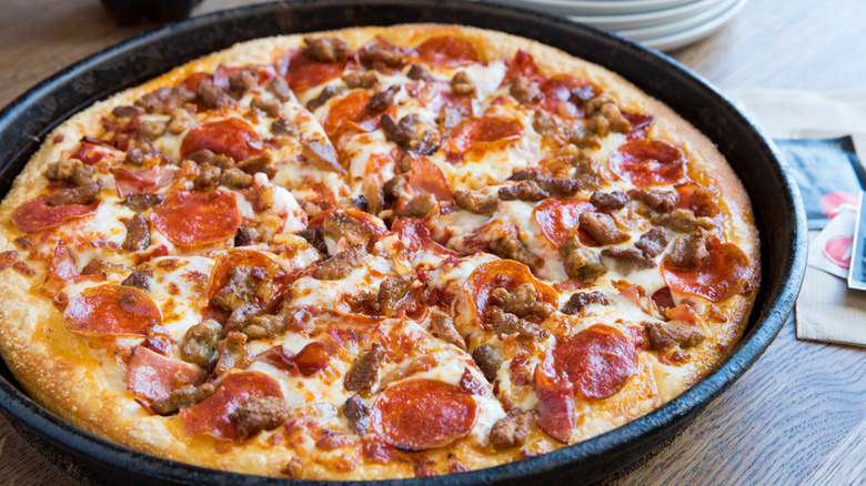 Pizza with meat toppings from Pizza Hut inside black pan