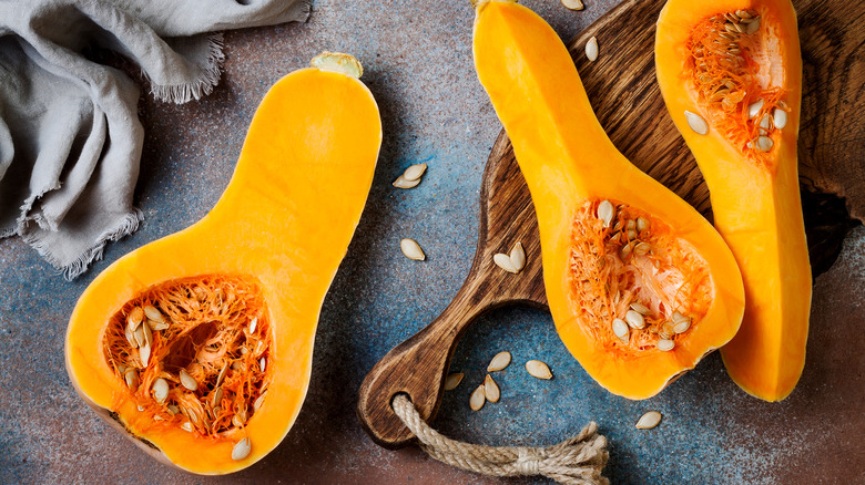 Several butternut squashes sliced open with their seeds scattered around them