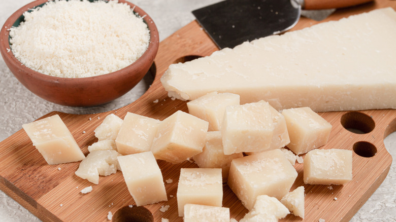 Wedge of Parmigiano cheese with hunks and bowl of grated cheese