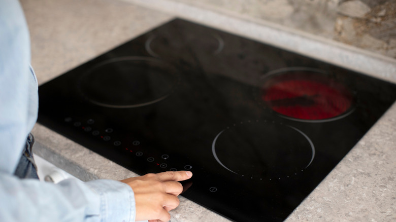 A person turning an induction range on
