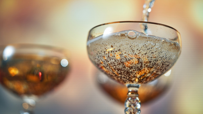 Close-up of sparklng wine being poured into a coupe glass