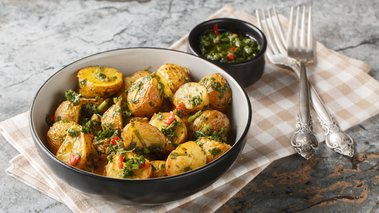 A bowl of perfectly crispy roasted potatoes garnished with herbs and peppers