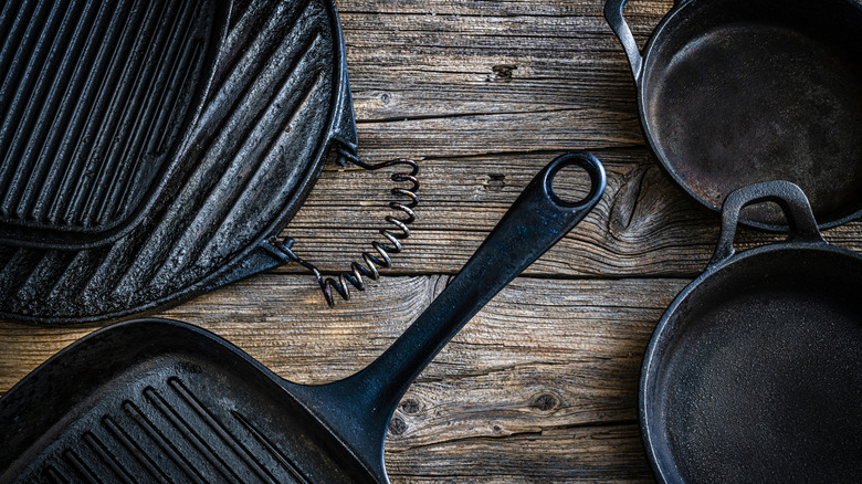 Various cast iron pans on a wooden table