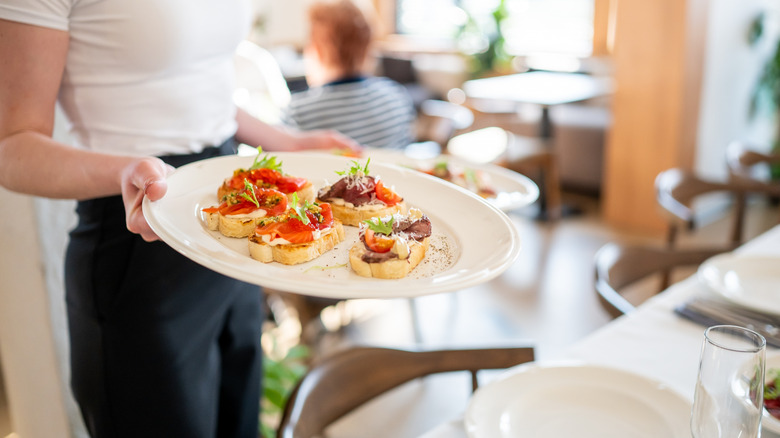 Woman holding a plate of bruschetta in a restaurant