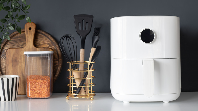 bucket-style air fryer on counter with cooking tools
