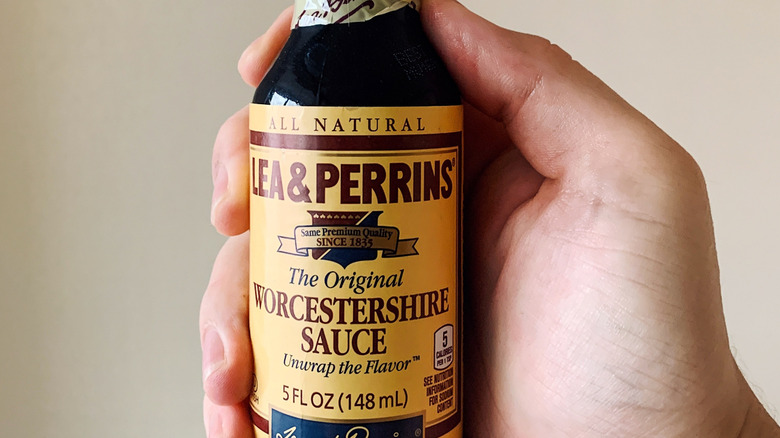 Hand holding a bottle of Worcestershire sauce
