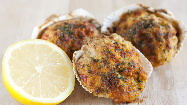 Three stuffed clams sit next to half a lemon.