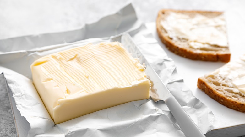 butter with knife and pieces of buttered bread