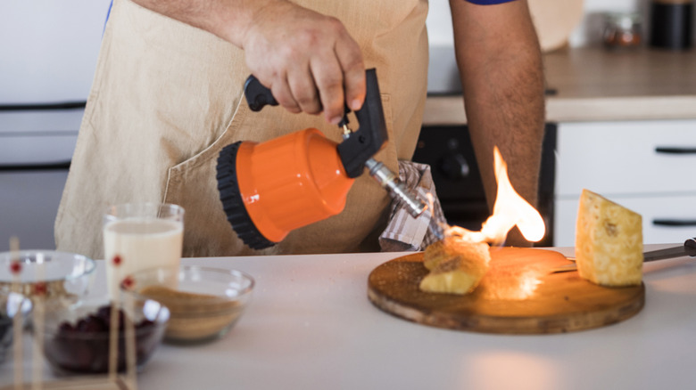 close up of person lighting dish with torch