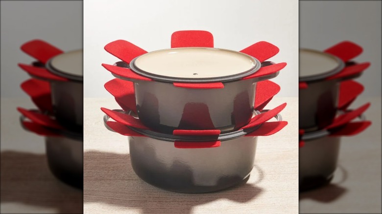 Le Creuset pans stacked with red felt protectors in between