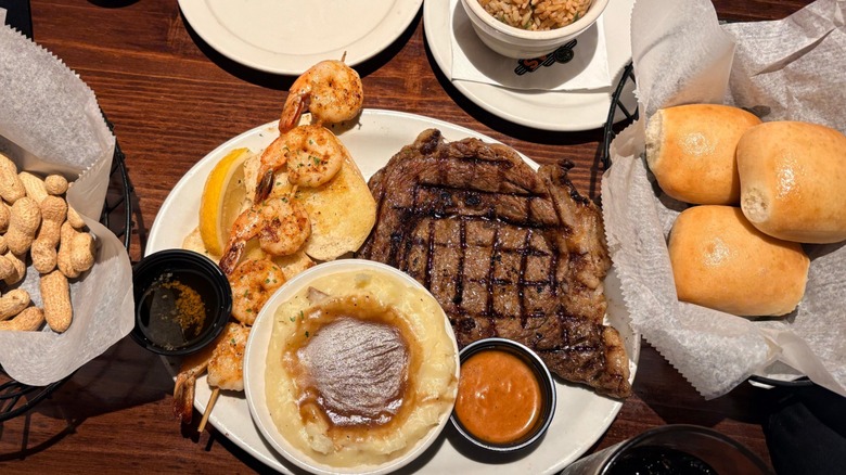 Texas Roadhouse steak with various sides, and baskets with rolls and peanuts