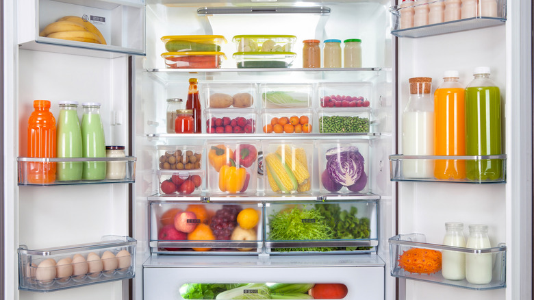 Neatly organized refrigerator with clear storage containers with colorful foods in them.