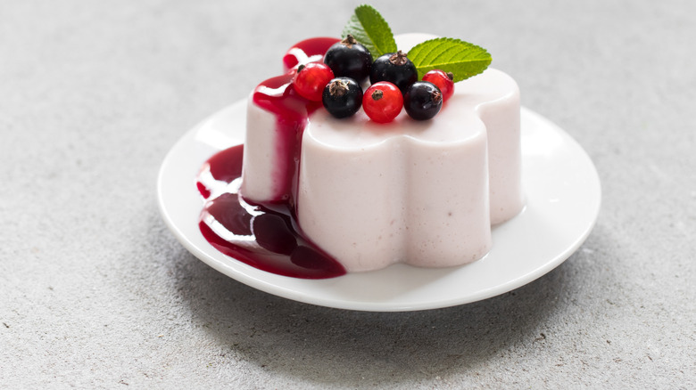 A plate of panna cotta topped with berries and berrry sauce