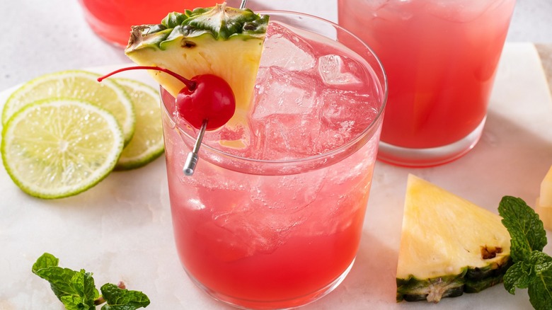 Closeup of a Singapore Sling cocktail with lime and pineapple garnishes