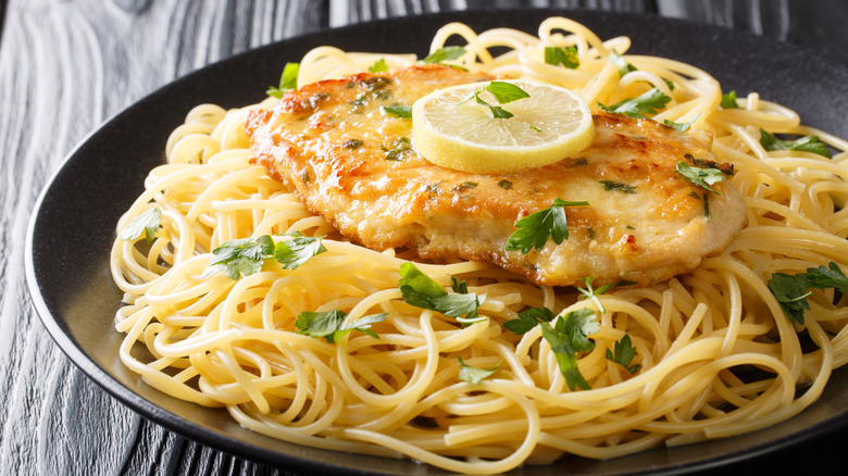 plate of chicken française with noodles and lemon