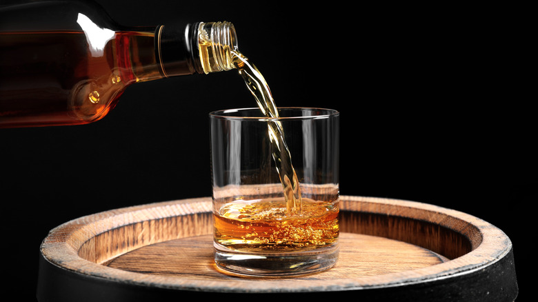 pouring whiskey into glass tumbler