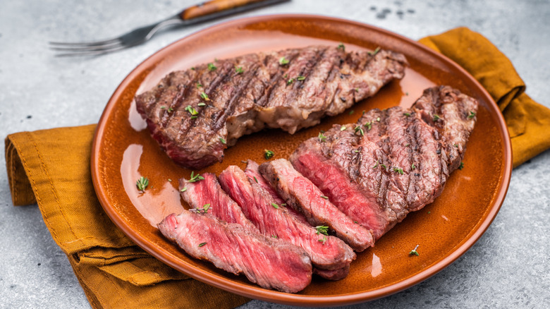 Grilled, sliced flat iron steak on an orange plate