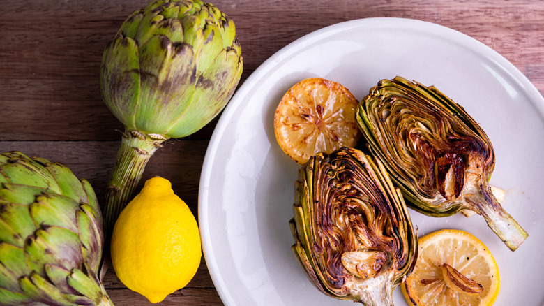 grilled artichokes and lemon on a white plate