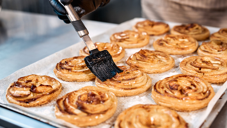 Using pastry brush to apply egg wash to cinnamon rolls