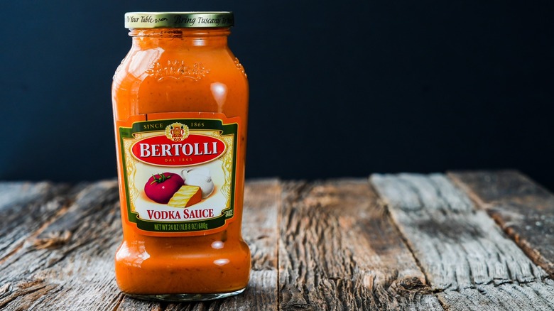 A jar of Bertolli vodka sauce on a wooden table