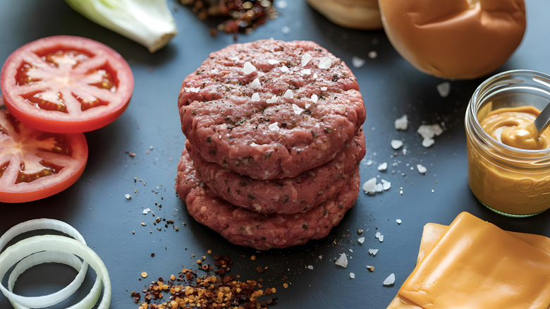 raw burgers with seasoning