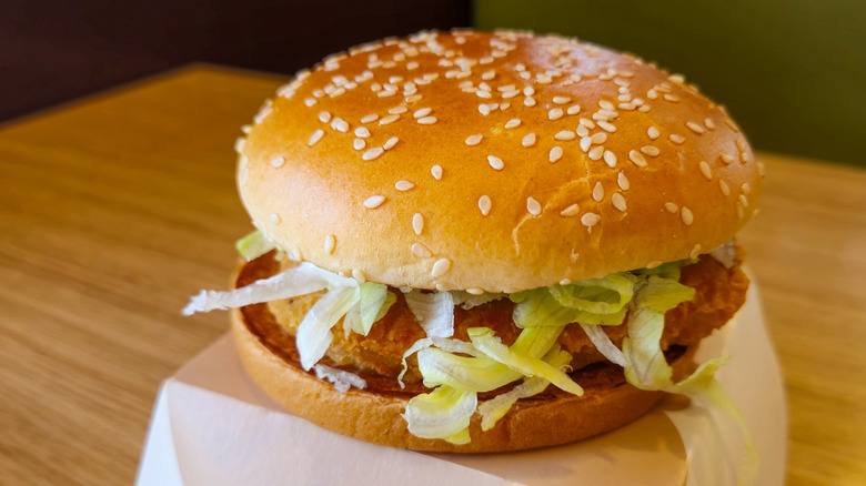 a McDonald's McChicken sandwich sitting atop the cardboard box it came in on a wooden table