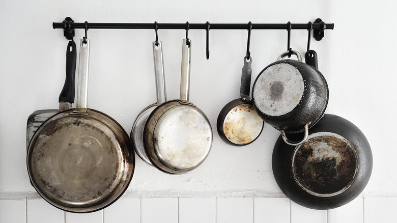 cooking pans hanging from rack on white wall