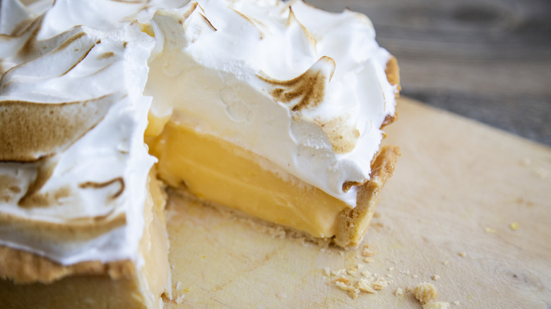 A golden brown toasted meringue topping covers a vibrant yellow lemon custard filling on a thin buttery pie crust