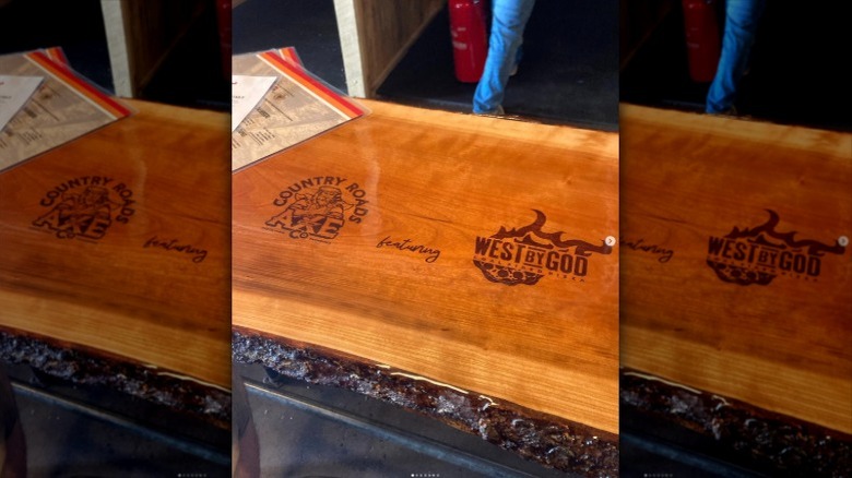Logos on wooden surface of Country Roads Axe Co and West By God