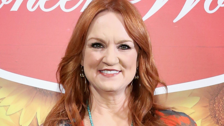 Ree Drummong smiles in printed cover up with black shirt and turquoise necklace