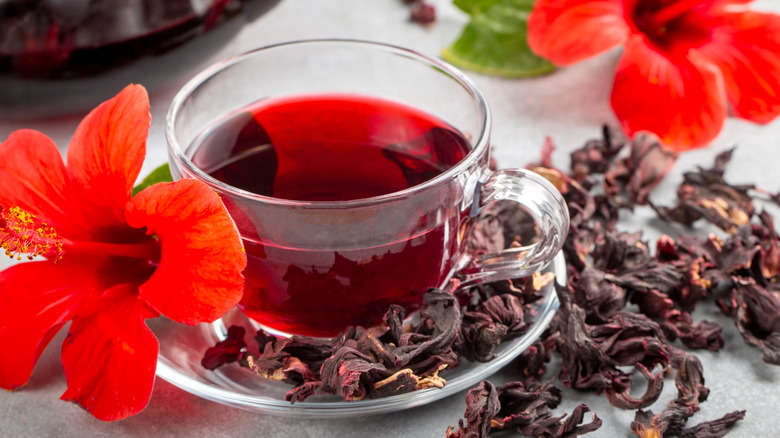 hibiscus tea in glass cup surrounded by flowers