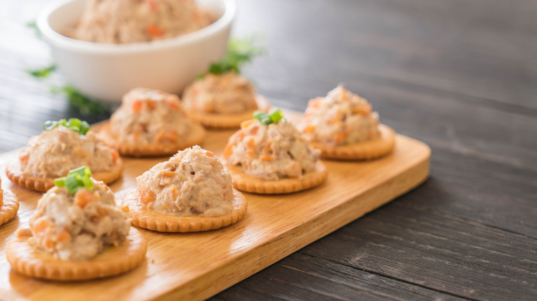 tuna salad on crackers for appetizer on wood board