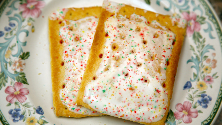 A floral China plate holding two frosted toaster pastries with sprinkles