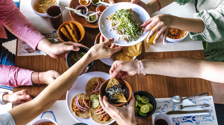 Aerial view of people passing plates of Mexican food at a restaurant