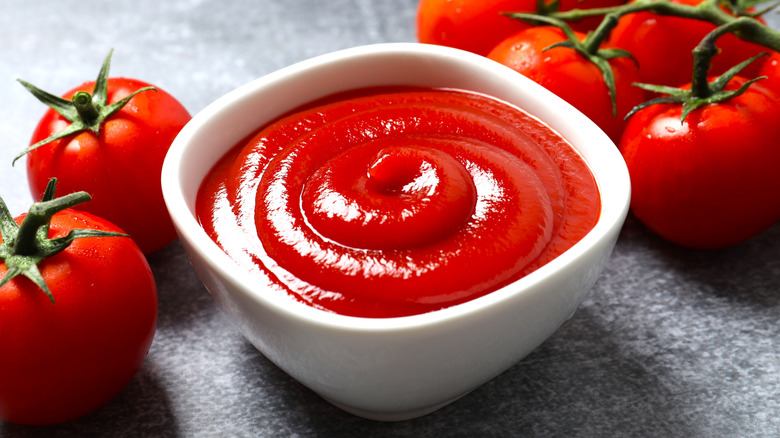 Bowl of ketchup next to tomatoes