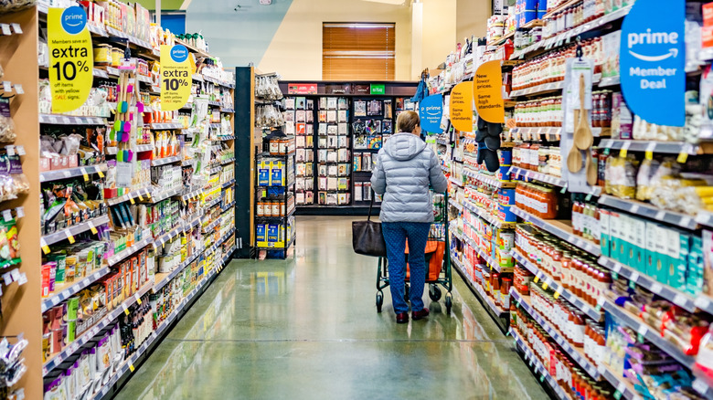 woman pushing shopping cart down aisle of Whole Foods