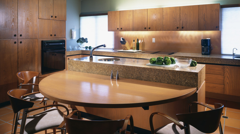 A rustic, 1980s kitchen with wood paneled kitchen cabinets